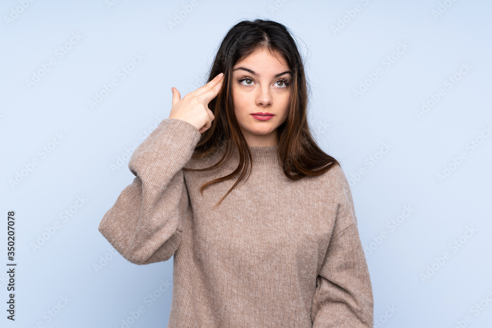 Young brunette woman wearing a sweater over isolated blue background with problems making suicide gesture Young brunette woman wearing a sweater over isolated blue background with problems making suicide gesture