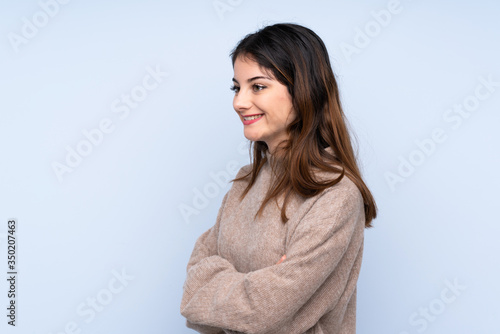 Young brunette woman wearing a sweater over isolated blue background in lateral position © luismolinero