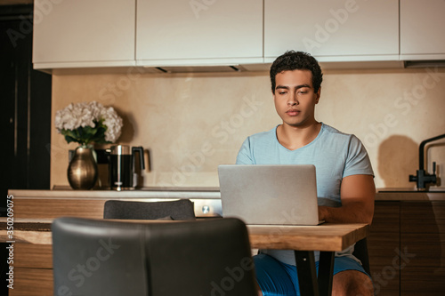 handsome male mixed race freelancer working with laptop on kitchen during quarantine © LIGHTFIELD STUDIOS