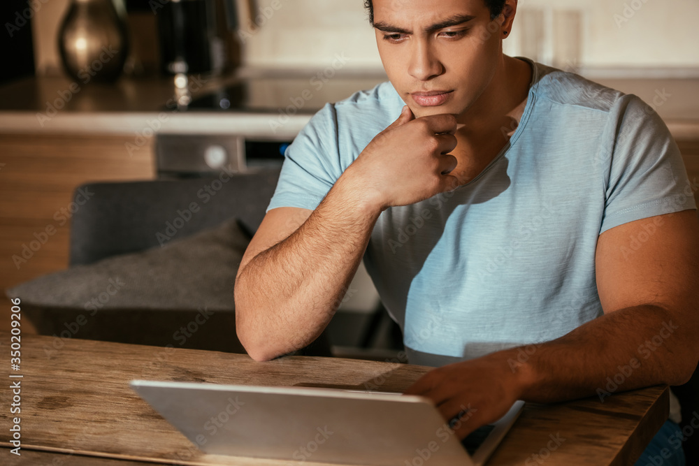 thoughtful mixed race freelancer working with laptop on kitchen during quarantine thoughtful mixed race freelancer working with laptop on kitchen during quarantine