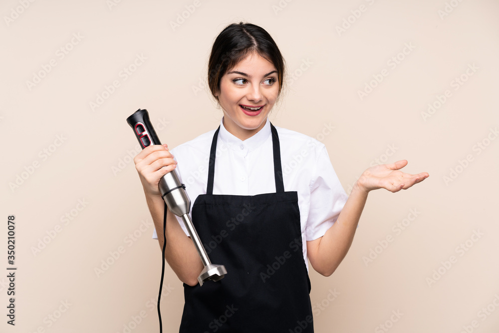 Young woman using hand blender over isolated background with surprise facial expression Young woman using hand blender over isolated background with surprise facial expression