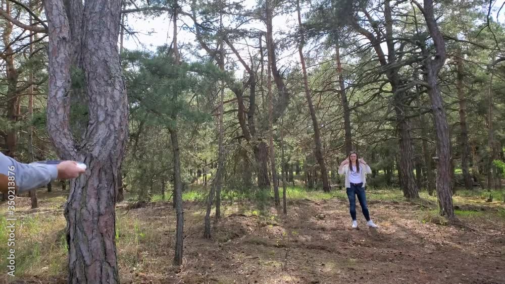 Leisure activity concept. Young brunette man playin frisbee with a woman in a pine forest clearing Leisure activity concept. Young brunette man playin frisbee with a woman in a pine forest clearing