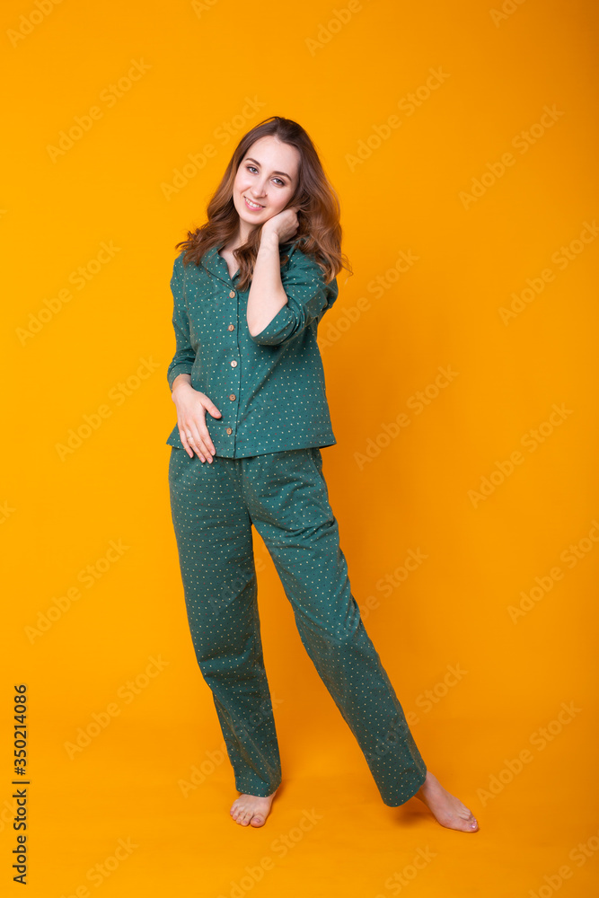 Smiling young girl in pajamas home wear posing while resting at home isolated on yellow background studio portrait. Relax good mood lifestyle concept. Smiling young girl in pajamas home wear posing while resting at home isolated on yellow background studio portrait. Relax good mood lifestyle concept.