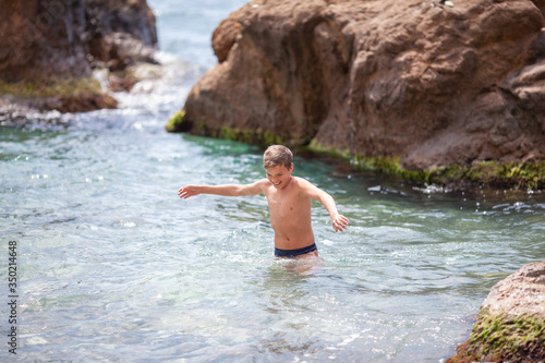 Happy beautiful teenager is swimming in the sea, a boy comes out of the water