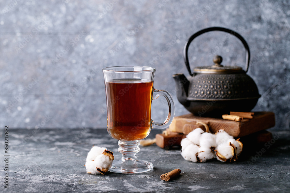A black metal teapot and a cup of tea in glass cup A black metal teapot and a cup of tea in glass cup