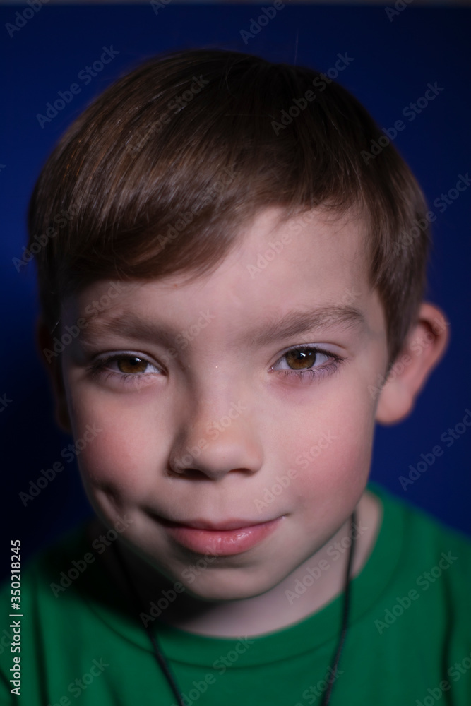 portrait of a happy peaceful nine year old blond boy smiling on a blue background portrait of a happy peaceful nine year old blond boy smiling on a blue background