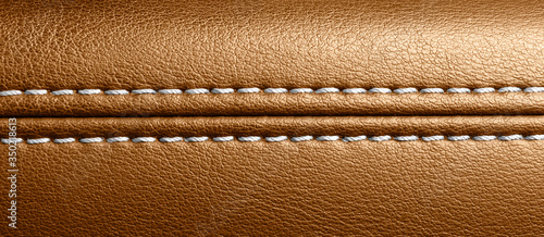 Car brown leather interior. Part of perforated leather door handle details. Orange Perforated leather texture background. Texture, artificial leather with stitching. Comfortable perforated leather