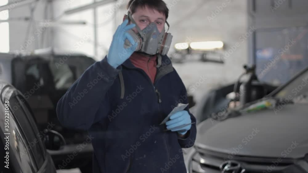 Worker at car service station stands in front of the camera and shows OK gesture Worker at car service station stands in front of the camera and shows OK gesture