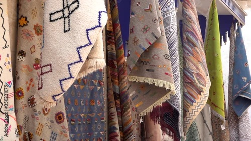 Multicolor arabian style carpets moving with wind on street market in Morocco, close up