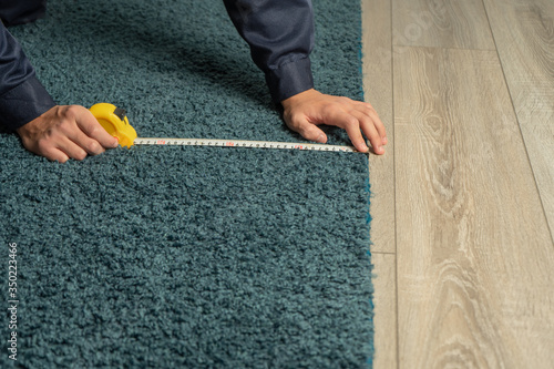 A store employee measures the length of a carpet for a customer