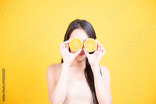 Beautiful Asian women smile happyness holding fresh orange slide with a yellow background.Squeeze Fresh oranges healthy fruits that are vitamin C.