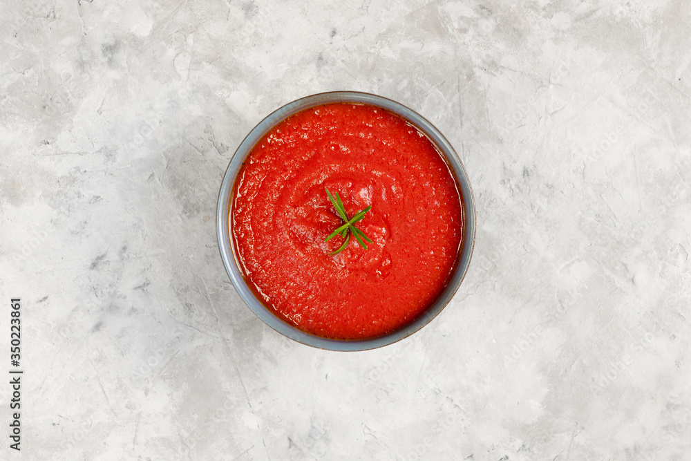 Tomato soup in a bowl decorated with rosmary on gray stone background Tomato soup in a bowl decorated with rosmary on gray stone background