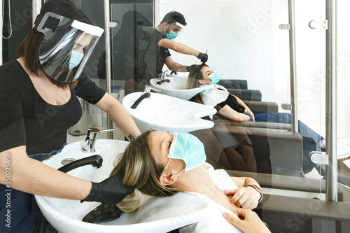 Servizio di lavaggio capelli dentro un salone da parrucchieri con tutte le disposizioni di protezione quali mascherine facciali, distanziamento , pannelli in plexiglass ecc photo