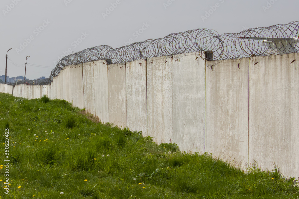 Concrete wall with barbed wire. Border wall, prison wall Concrete wall with barbed wire. Border wall, prison wall