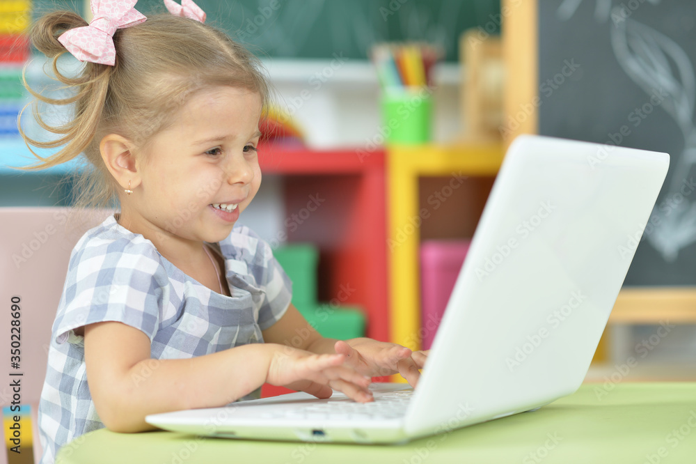 Portrait of curious little girl using laptop at desk Portrait of curious little girl using laptop at desk