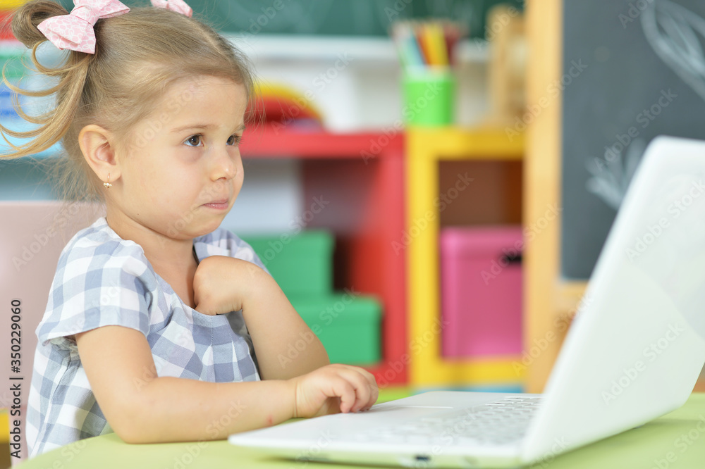 Portrait of curious little girl using laptop at desk Portrait of curious little girl using laptop at desk
