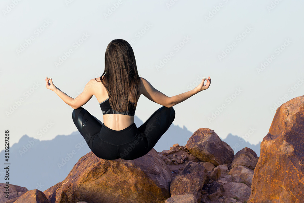 A thin athletic girl takes a break between classes on the background of mountains in the early morning, enjoys silence and freedom. A thin athletic girl takes a break between classes on the background of mountains in the early morning, enjoys silence and freedom.