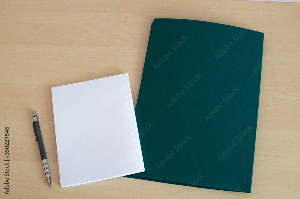 white notebook with dark green folder on the wooden table white notebook with dark green folder on the wooden table