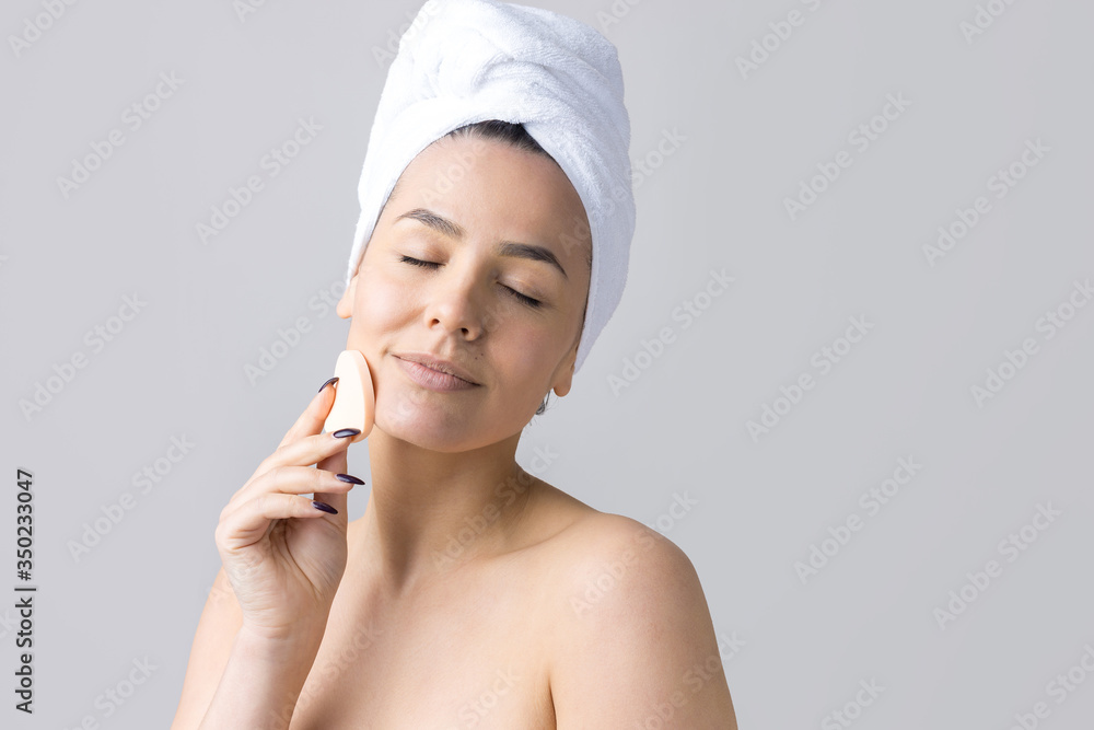 Beauty portrait of woman in white towel on head with a sponge for a body in view of a pink heart. Skincare cleansing eco organic cosmetic spa relax concept. Beauty portrait of woman in white towel on head with a sponge for a body in view of a pink heart. Skincare cleansing eco organic cosmetic spa relax concept.