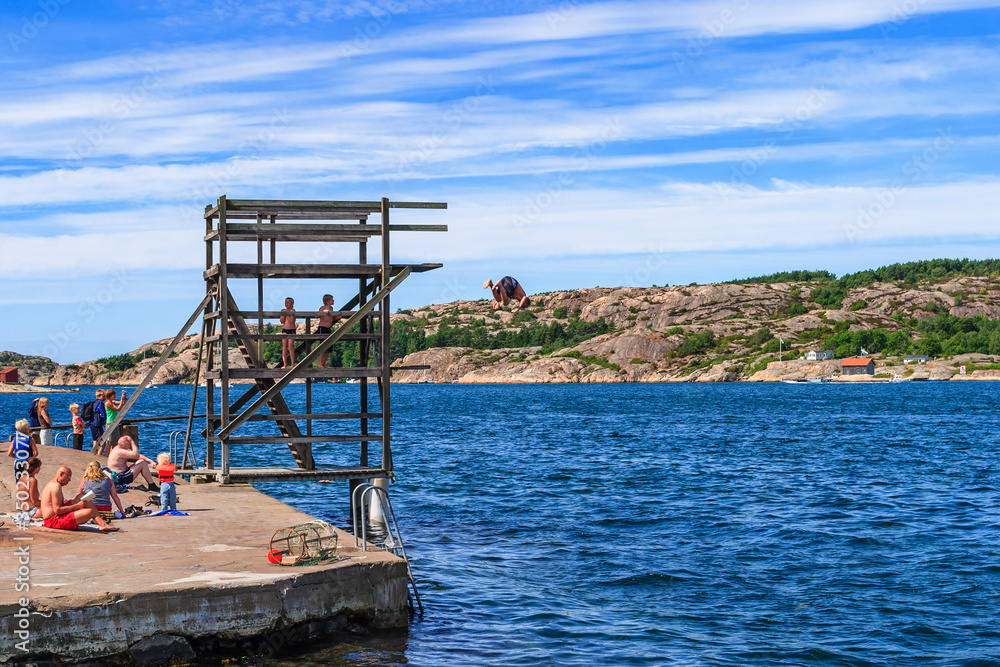 Beach by the sea with people sunbathing and bathing and jumping from a jumping tower Beach by the sea with people sunbathing and bathing and jumping from a jumping tower