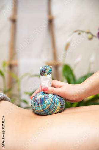 Calm young woman enjoying massage with herbal bags
