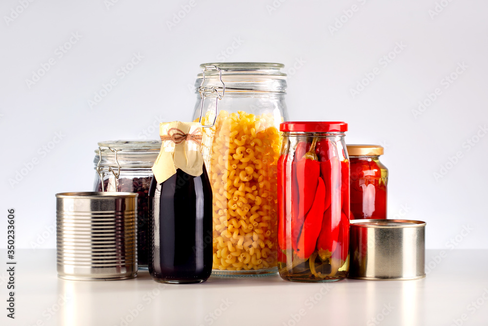 Foto Stock Different glass jars with grains, pasta, vegetable, cans of  canned food on the table. | Adobe Stock
