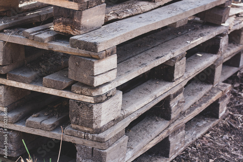Old pallets are stacked. Old dirt on pallets. Tinted. Horizontal.