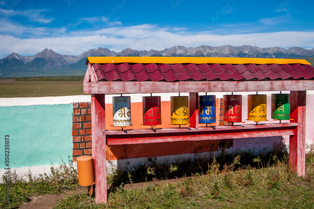 Tibetan prayer wheels. Buddhist spinning drums. Multi-colored drums under the roof. Mountains on the horizon. Horizontal. Tibetan prayer wheels. Buddhist spinning drums. Multi-colored drums under the roof. Mountains on the horizon. Horizontal.