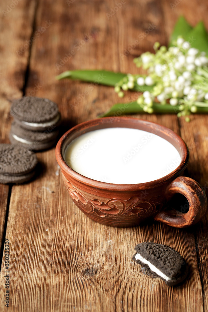 On a wooden table is a cup with milk and chocolate cookies.
On a wooden table is a cup with milk and chocolate cookies.