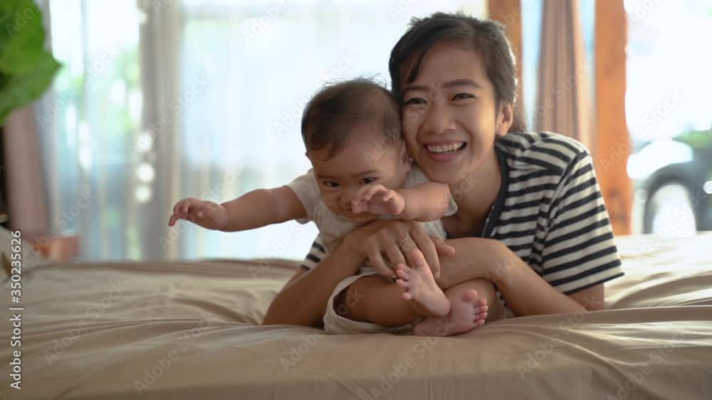 happy asian mother playing together with her baby on the bed happy asian mother playing together with her baby on the bed