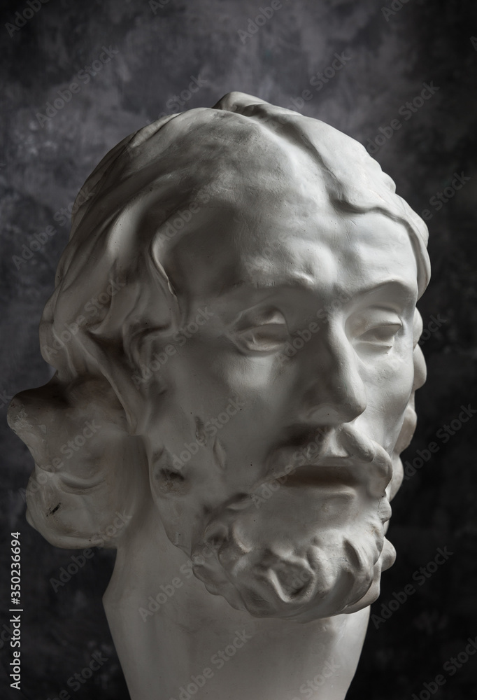Gypsum copy of ancient statue John the Baptist head on dark textured background. Plaster sculpture man face. Gypsum copy of ancient statue John the Baptist head on dark textured background. Plaster sculpture man face.