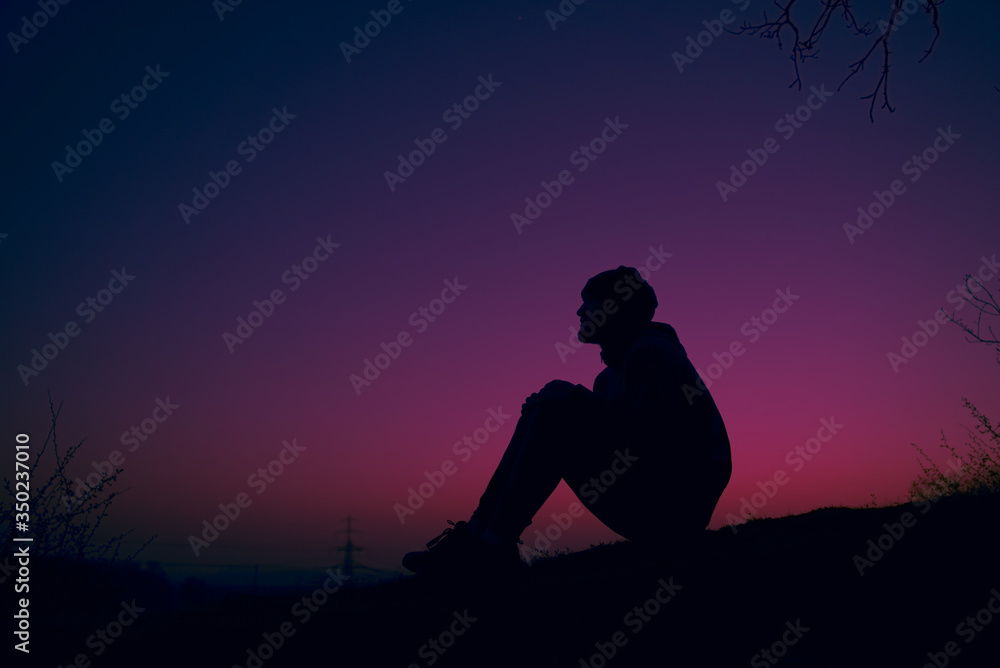 Silhouette of man sitting on swinging hill dreaming at sunset
