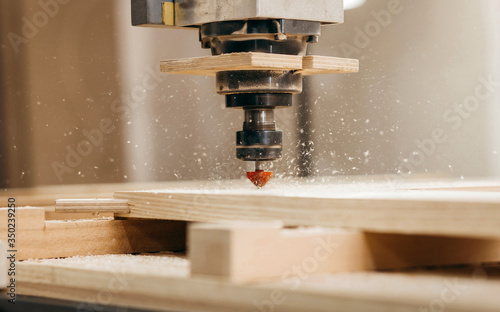 Close-up of cutting wood on a CNC milling machine in garage photo