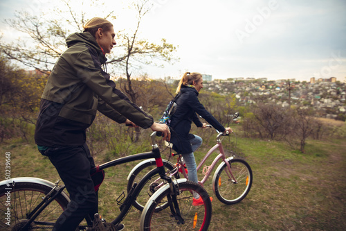 Fototapeta Naklejka Na Ścianę i Meble -  Best friends having fun near countryside park, riding bikes, spending time healthy. Calm nature, spring day, positive emotions. Sportive, active leisure activity. Traveling or walking together.