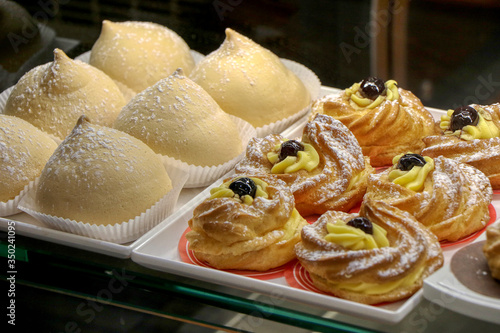 Zeppole and tette delle monache for breakfast in a shop window of an Italian bar photo