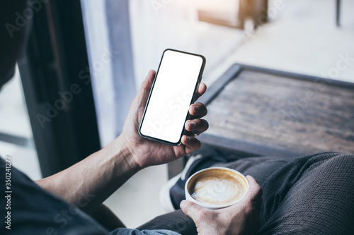 cell phone Mockup image blank white screen.man hand holding texting using mobile on desk at coffee shop.background empty space for advertise.work people contact marketing business,technology