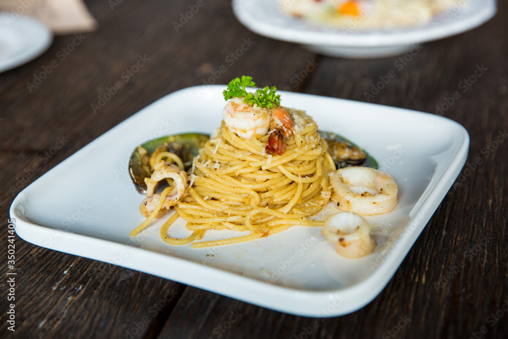 Seafood spaghetti in a white plate on an old wooden table