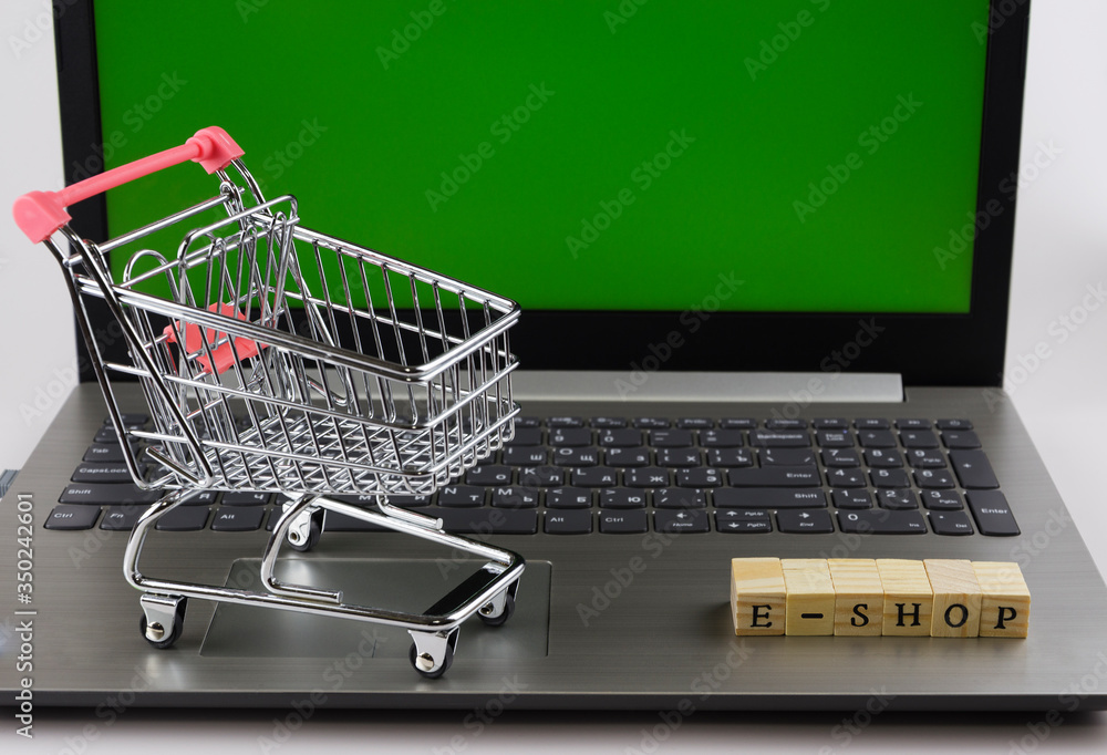 e - shop folded with cubes with letters on the background of a laptop and trolley 3