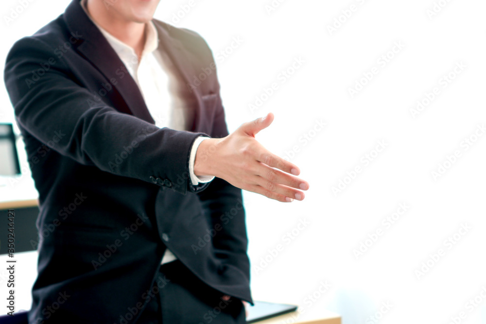 Young confident smart businessman in office, man standing and reaching hand for handshake at the workplace Young confident smart businessman in office, man standing and reaching hand for handshake at the workplace