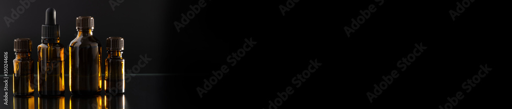 Aromatherapy essential oil dropper bottle, black background. Long dark banner Aromatherapy essential oil dropper bottle, black background. Long dark banner