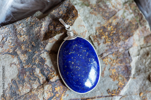 Beautiful lapis lazuli mineral stone pendant on rocky background