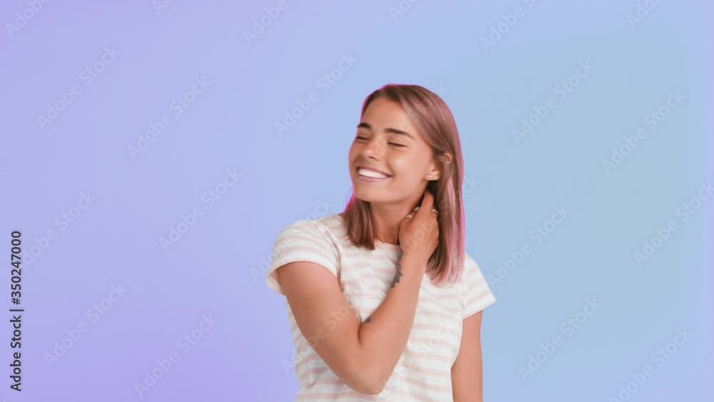 Young lady with pink hair and tattooed hands, dressed in striped t-shirt. She is smiling and winking, posing against purple background. Close up Young lady with pink hair and tattooed hands, dressed in striped t-shirt. She is smiling and winking, posing against purple background. Close up