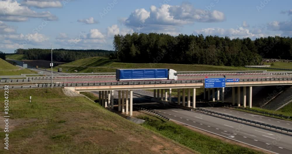 Truck rides on bridge and continues to move along highway. Aerial view. Truck rides on bridge and continues to move along highway. Aerial view.
