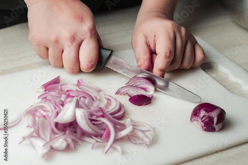 woman cutting fresh white onion with knife