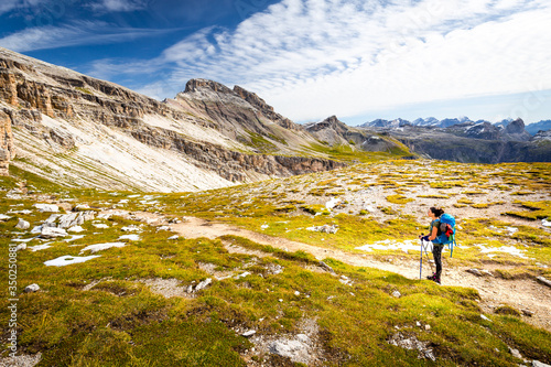 Backpacker female tourist hiking alone alpine mountains footpath Italy.
