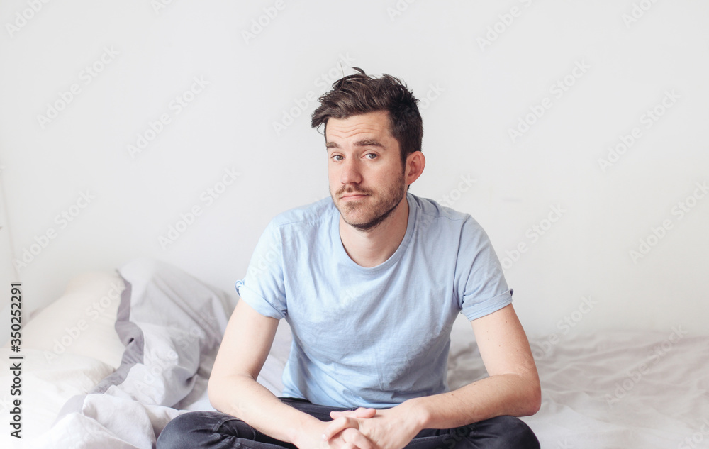 Young man has a funny look, sitting in bed