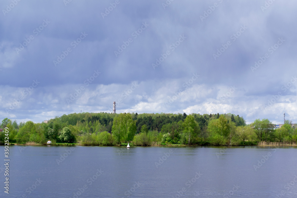 Obraz premium Stormy sky reflected in the river and forest in the background. Before the rain