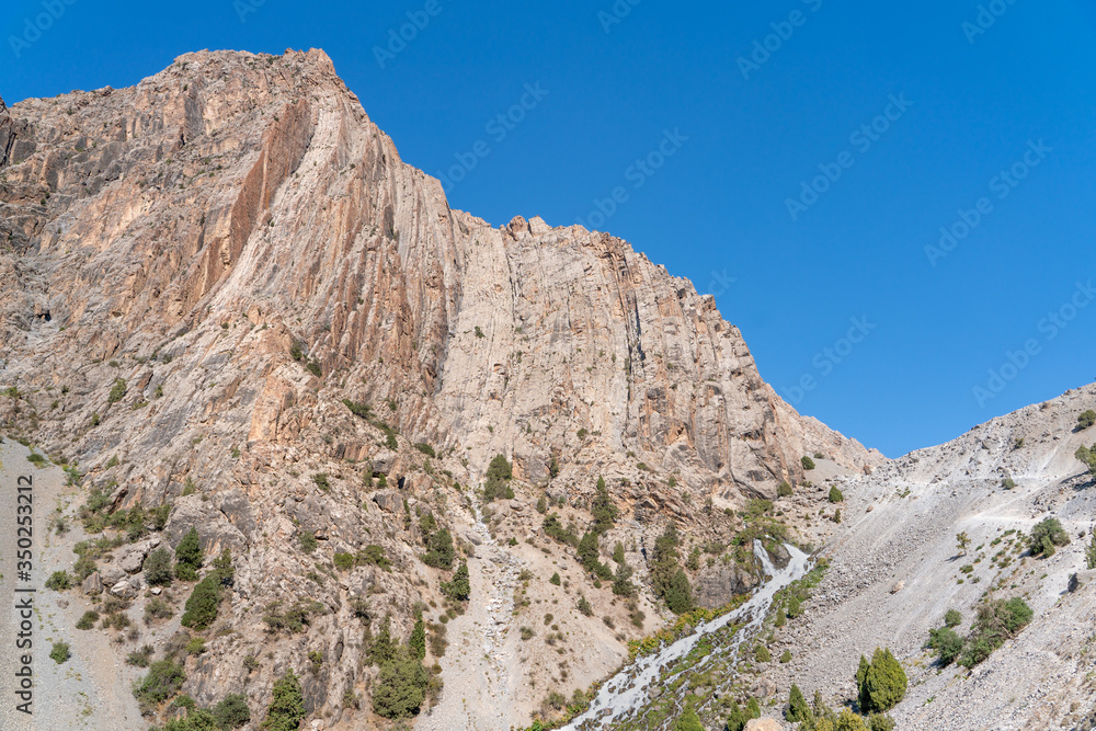 The beautiful mountain trekking road with clear blue sky and rocky hills in Fann mountains in Tajikistan