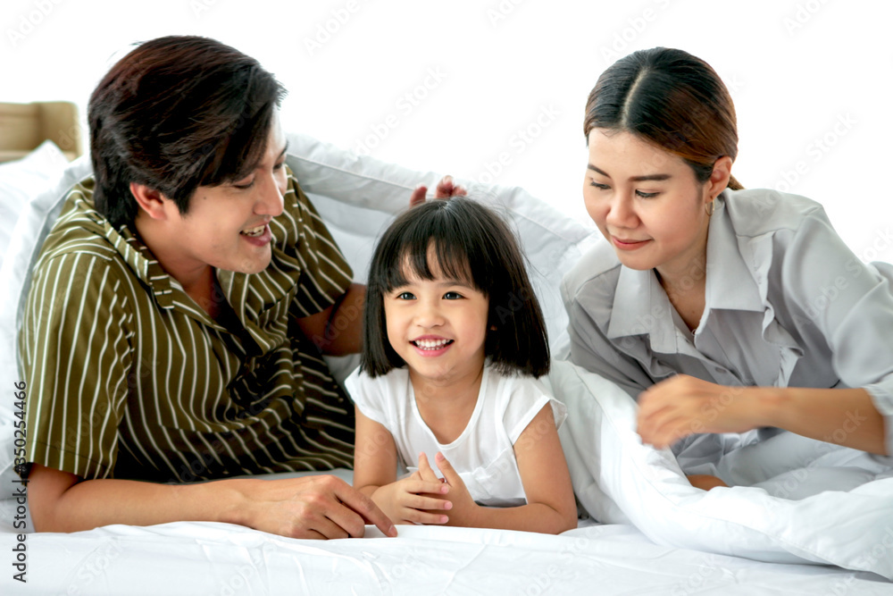 Happy family having fun in the bedroom. Father, mother and daughter lying on bed and spending time together, parents and kid having good memory and playing together at home Happy family having fun in the bedroom. Father, mother and daughter lying on bed and spending time together, parents and kid having good memory and playing together at home