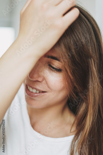 Close up portrait of smiling young woman brown hair and green eyes with freckles in white t-shirt